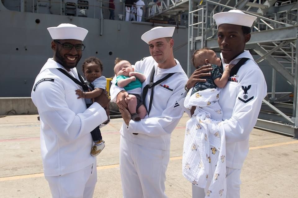 Navy sailors holding babies at homecoming